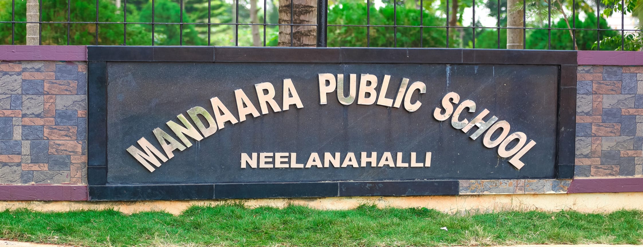 The entrance sign at Mandaara Public School, Neelanahalli, set in metal letters on a stone wall.